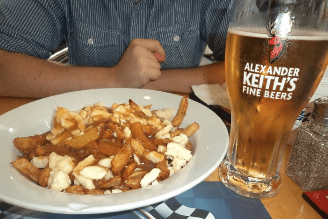 Enjoying the typical cuisine of Québec: the poutine (fries with cheese and a brown secret sauce) next to a local beer // Disfrutar de la cocina típica de Québec: la poutine (papas fritas con queso y una salsa secreta) al lado de una cerveza local - Picture by Andrea Arzaba